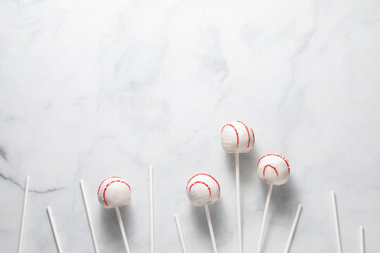 An arrangement of decorated cake pops with sticks against a light background.