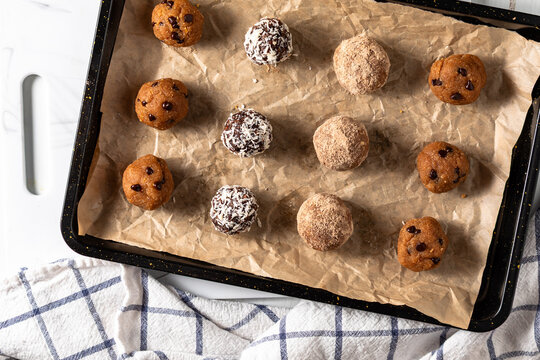 Assorted homemade energy balls on a parchment lined baking sheet.