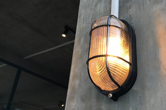 Warm Industrial Wall Light Fixture With Protective Cage Mounted on Concrete Interior Wall