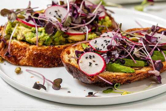 A close up of homemade avocado toast with various fresh toppings.