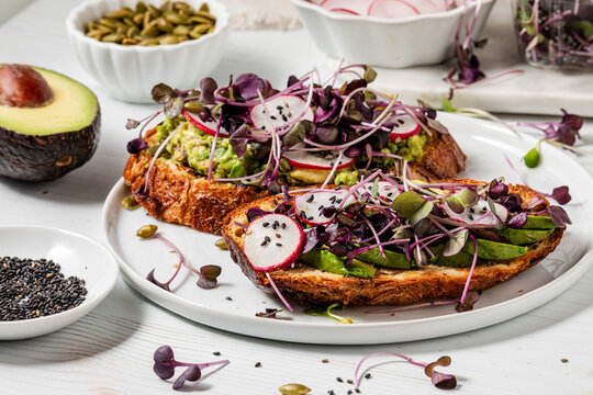 A serving of freshly made avocado toast with purple radish microgreens.