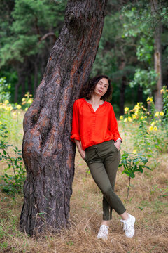 Woman Leaning on Tree in Red Blouse