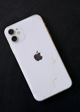 Kyiv, Ukraine. July 10, 2026. Broken back glass of a white iPhone 11 smartphone on a black background.