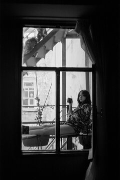 Woman drinks coffee on the fire escape stairs, black and white 