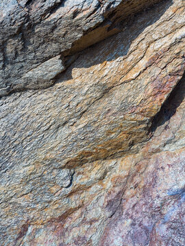 Close up of steep natural rock face with prominent layered textures and cracks