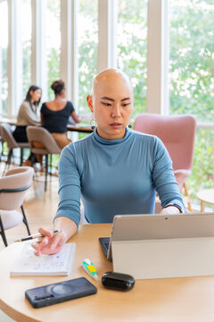 Stylish Businesswoman Works At The Office While Others Chat Nearby