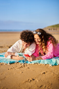 Young couple enjoying beach vacation scrolling social media