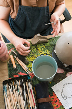 Creating Pottery With Tools and Water at a Workspace Table