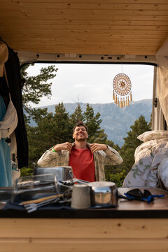Man Smiles in Camper While Preparing for Outdoor Adventure