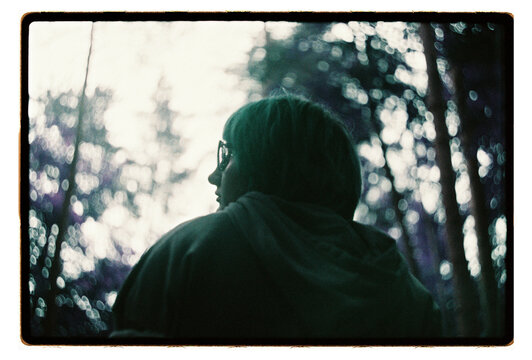 A young woman gazes into a softly blurred forest