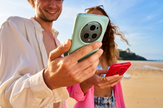 Happy couple checking smartphones on summer beach vacation