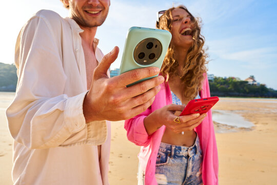 Happy couple using smartphones on beach vacation