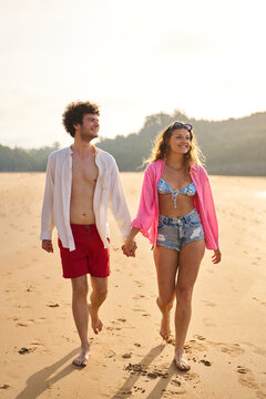 Couple walking barefoot on beach holding hands during vacation