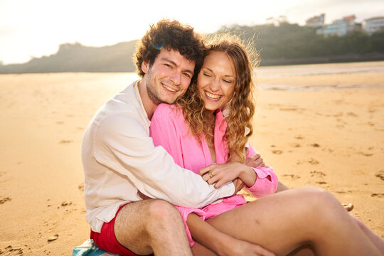 Loving couple embracing on beach during golden hour
