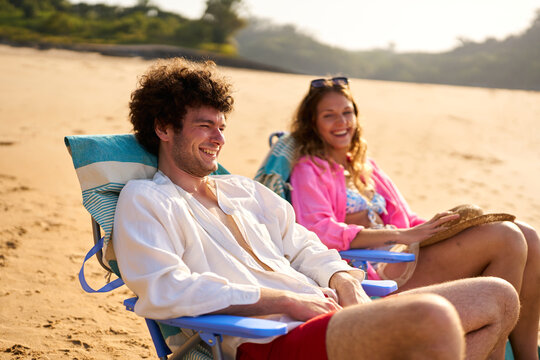 Happy couple relaxing on beach chairs during summer vacation