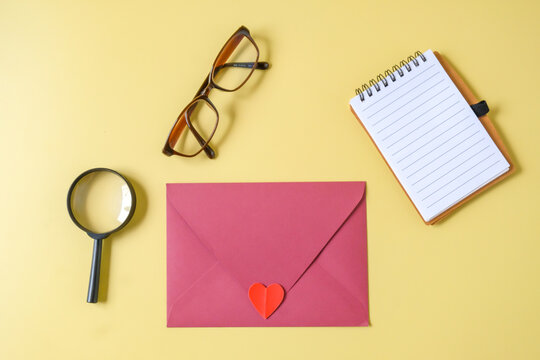 Pink paper envelope with mini heart sign on a color background.