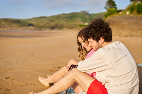 Young couple hugging on sandy beach during vacation