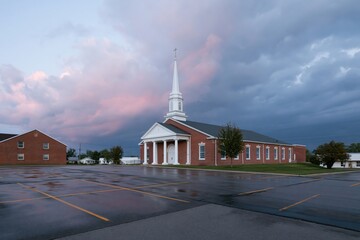 Obraz premium The Church in Soft Sunset Light with White Steeple and Red Brick Facade
