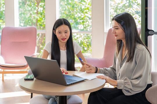 Two Women Discussing Work at a Table in a Bright Office Space