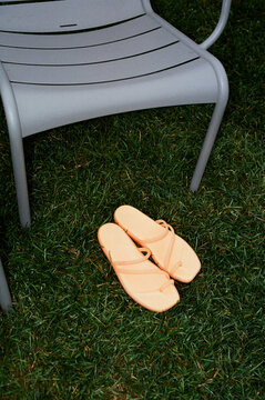 Sandals placed beside a chair on grassy ground 