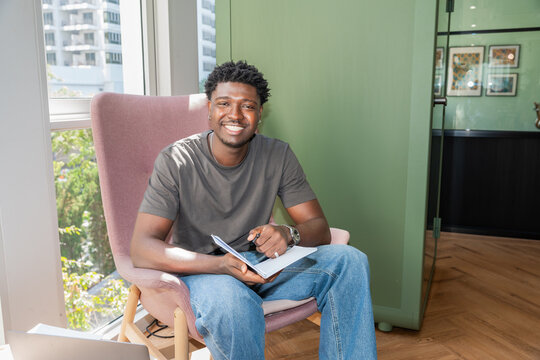Young Man Sitting in Chair Writing in Notebook During Daytime