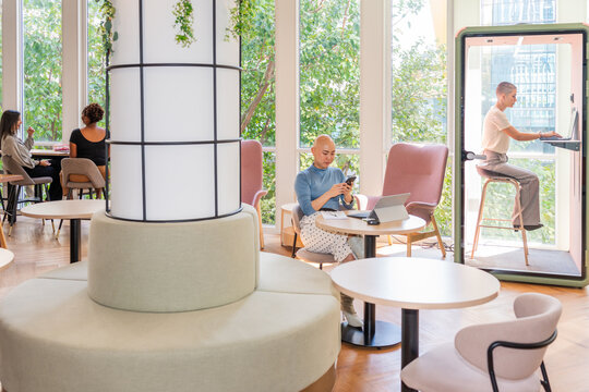 People Working and Relaxing in a Modern Cafe Space With Greenery