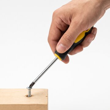 Hand using Phillips head screwdriver to screw into wood