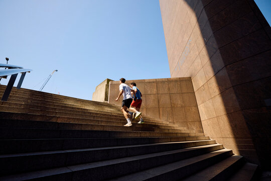 Two People Run up Stairs in a Sunny Outdoor Setting
