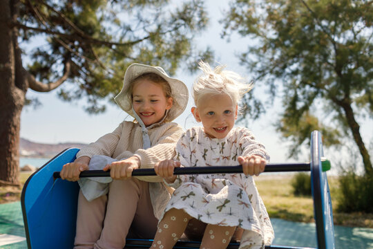 Children have fun on a spring rocker on a sunny day