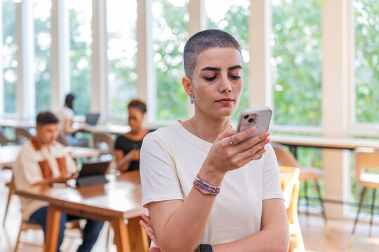 Woman Checking Her Phone in a Busy Office During Daylight Hours