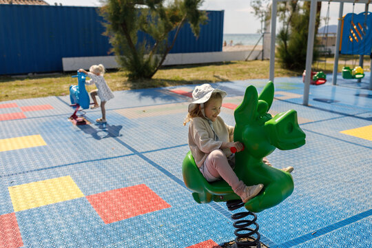 Children ride on a spring rockers on a sunny day