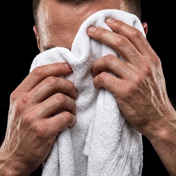 Man wiping sweat from his face with a white towel after intense physical activity