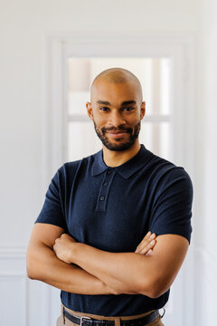 Man standing with crossed arms smiling confidently at camera