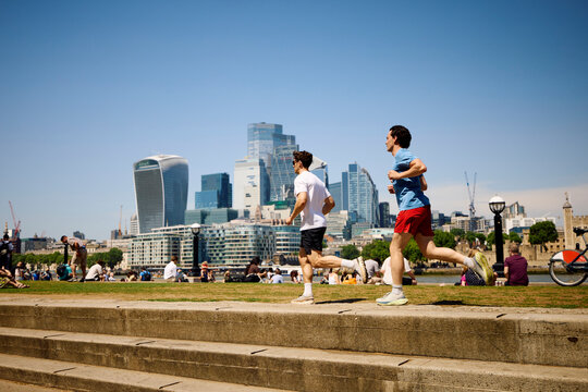 Friends Run Along Riverside Path in London