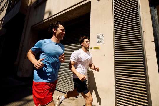 Active Men Run Together on a Sunny Street