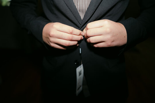 close up of hands of teen trying on suit 
