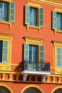 Stylish yellow and orange building facade with green window shades 