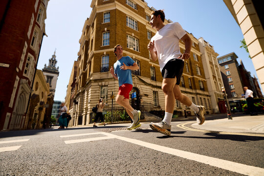 Men jog side by side on a bright street in the city of London