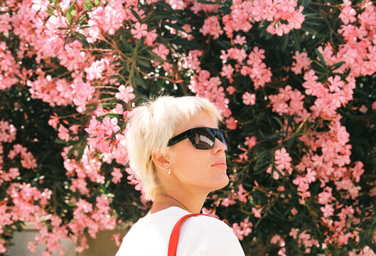 Person Stands Near Pink Flowers With a Sunny Background in Spring
