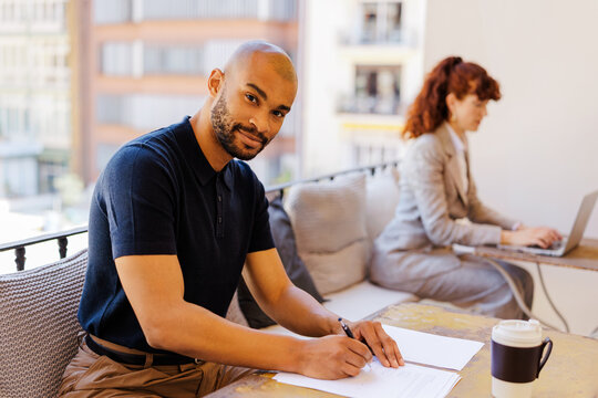 Professional man writing documents on outdoor balcony