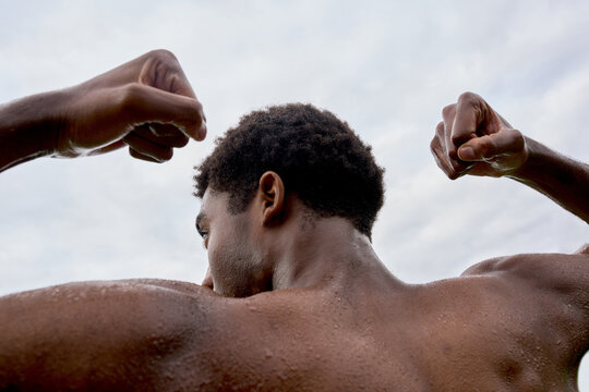 Strong Man Shows Muscles Against Cloudy Sky