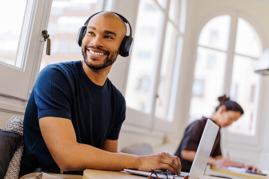 Man in headphones smiling while working remotely at office
