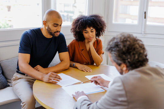 Couple consulting financial advisor discussing important documents
