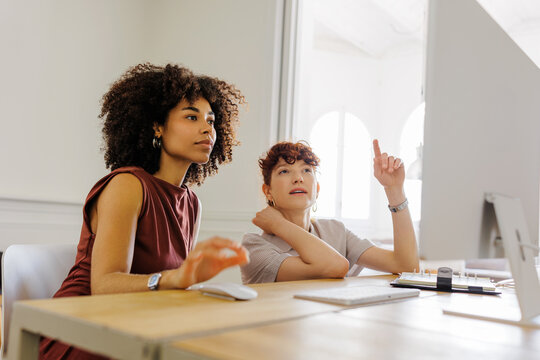 Professionals discussing ideas using computer together at office