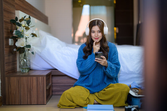 Asian woman thinking listening music using phone at home