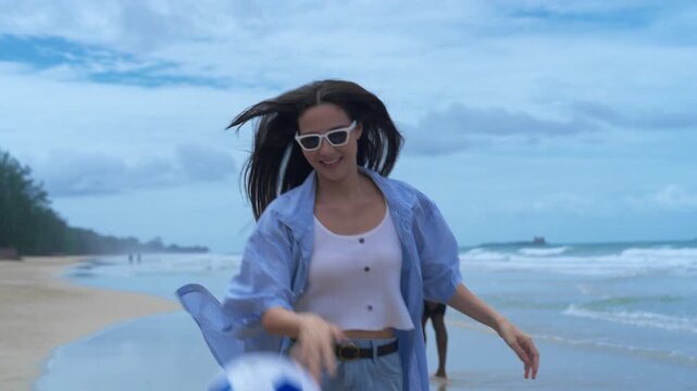 Close-up of a joyful young woman holding a soccer ball, radiating vitality and authentic happiness during an unplugged beach escape.