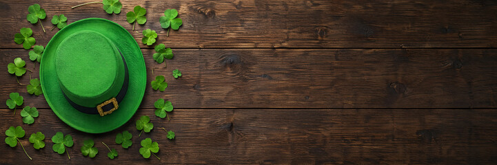 Green leprechaun hat with clover leaves on rustic wooden background