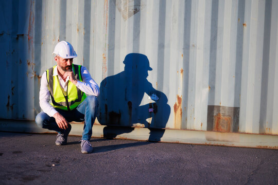 Handsome caucasian male dock foreman worker in white hard hat helmet and high-visibility vest working in Shipping Cargo Container Terminal Depot