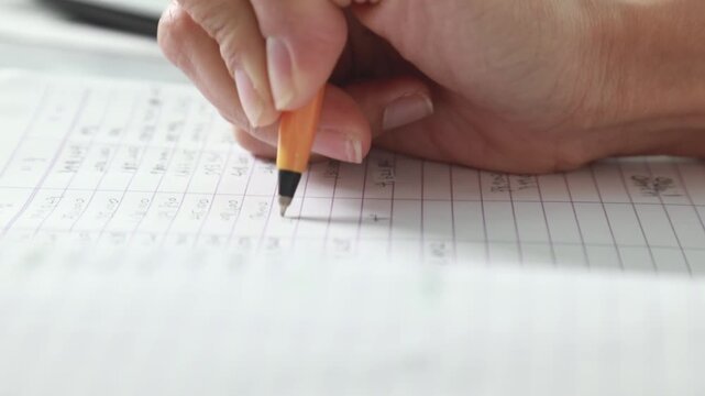사무실에서 업무 장부에 꼼꼼하게 수치를 확인하며 정산 내역을 필기하는 모습입니다.