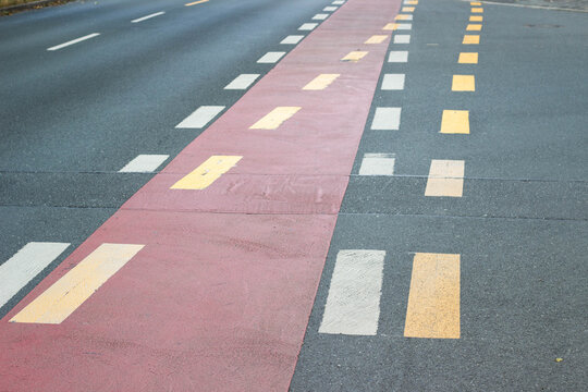 Road surface with distinct red and yellow lane markings, including dashed and solid lines, creating a clear traffic guide for vehicles and pedestrians